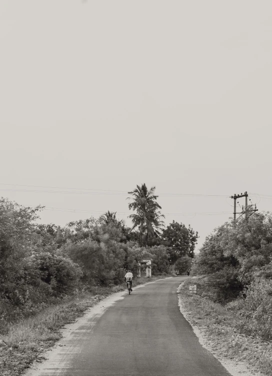 a person walking down the side of the road with a bike