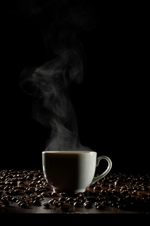 a white cup filled with steam sits next to coffee beans