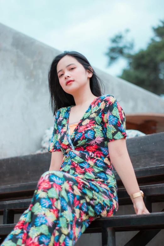 a woman with black hair is posing near a wall