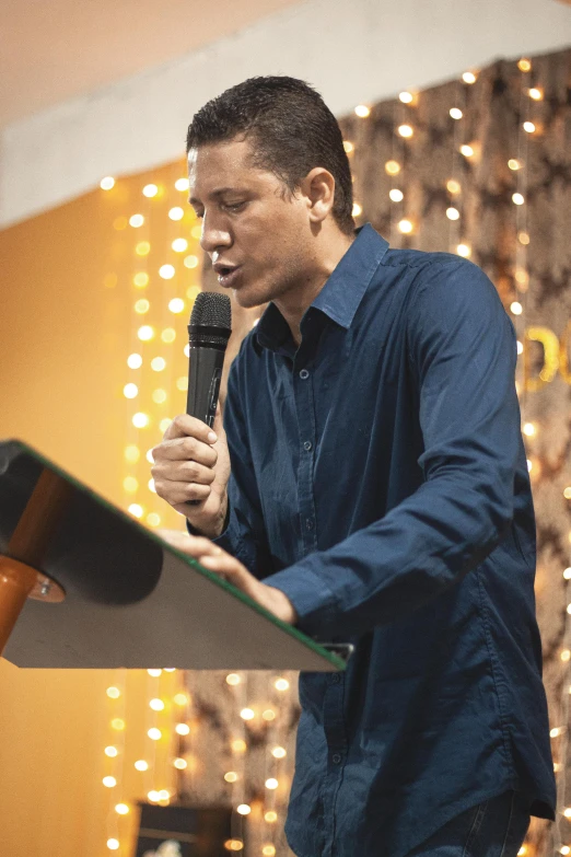 man speaking into a microphone in a stage setting