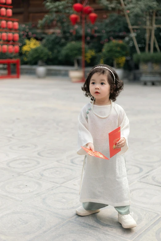 little girl dressed in white holding a red folder