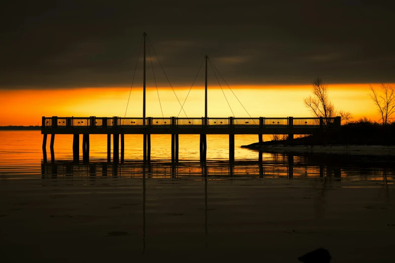 the sun sets over the ocean as boats sit on a dock