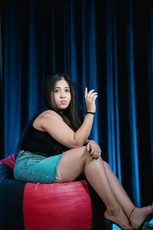 a young woman in a green and blue dress sitting on a bean bag chair