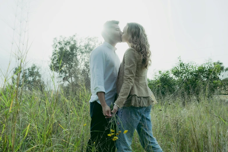 two people in the grass with each other and kissing