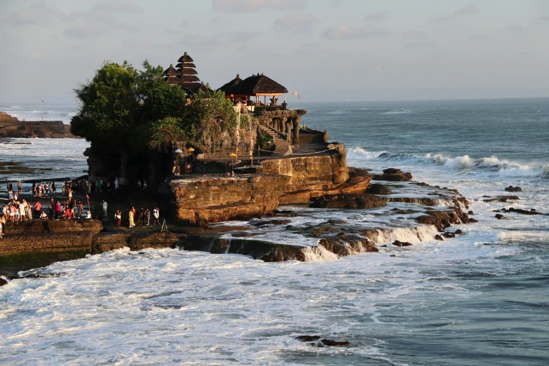 an ocean shore with people near some rocks and waves