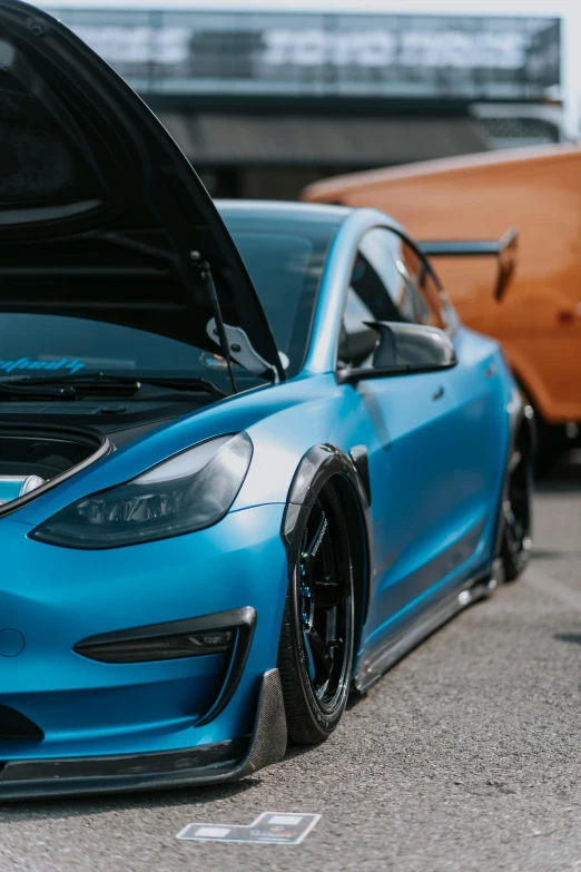 a blue car with a hood open sitting on the street