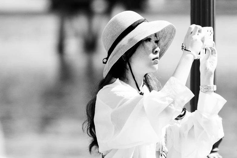 a woman wearing a floppy hat is playing with a cell phone