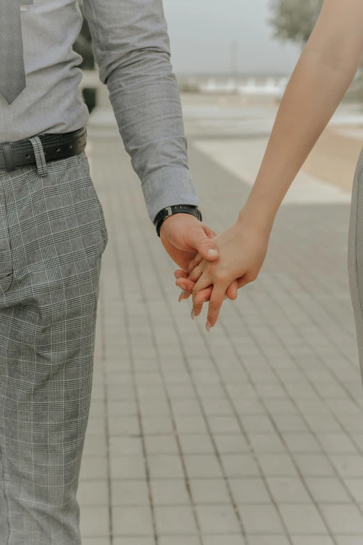 couple holds hands, walking across sidewalk with wet brick floor