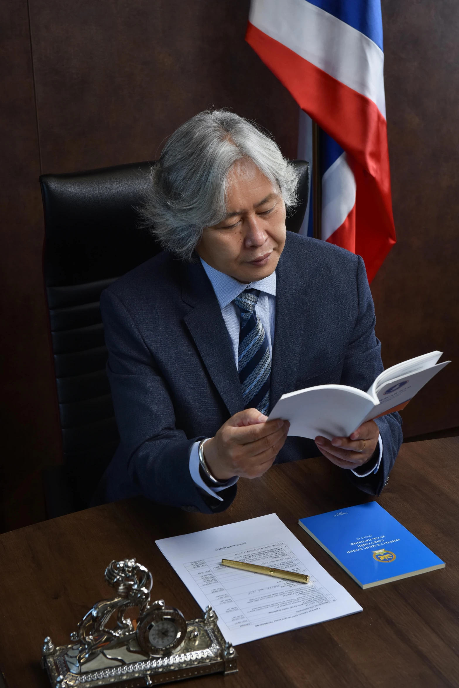 a man that is sitting at a desk reading a book