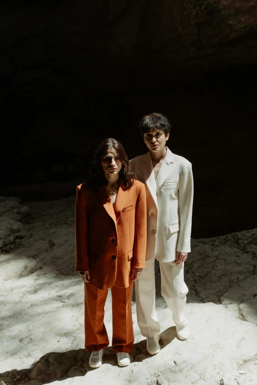 two women are standing side by side in white and orange