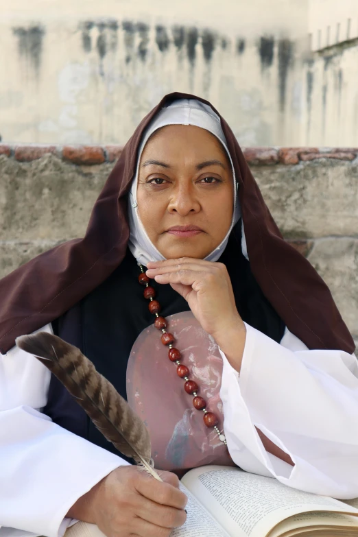 a nun holding a feather and a book