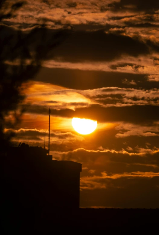 a sunset behind the dark clouds over a tower