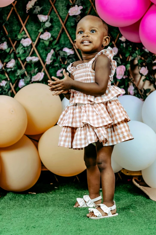 a small child is standing by balloons and smiling