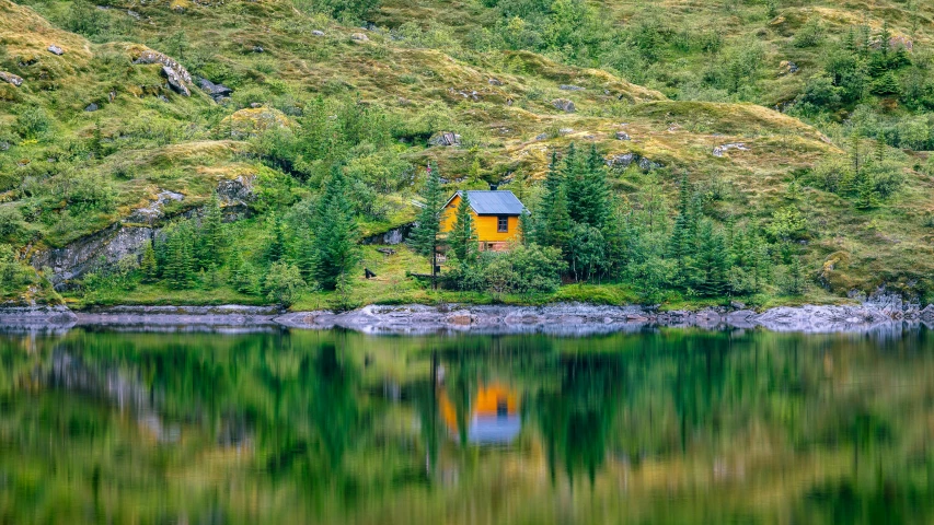 a cabin sits on the edge of a small lake