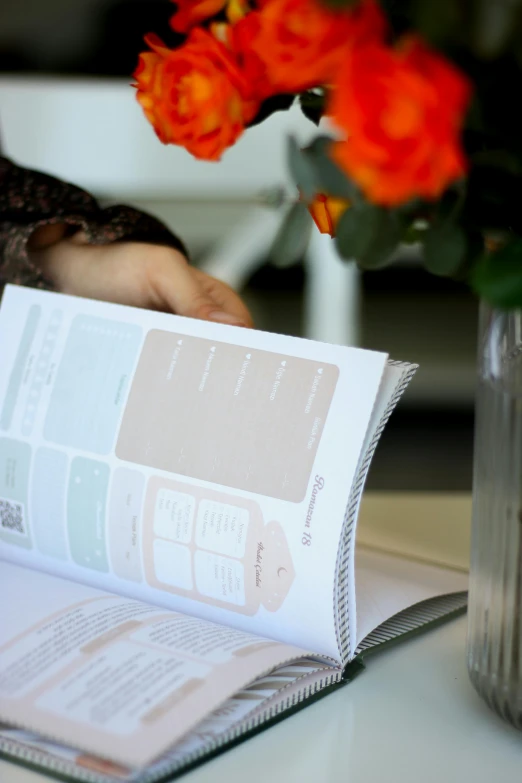 a person reads a piece of paper near orange flowers