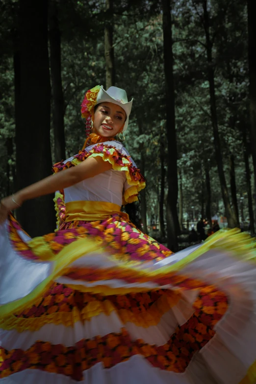 a woman is standing in the woods wearing a colorful dress