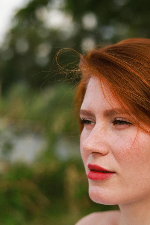 a woman with red hair and freckles is looking away from the camera