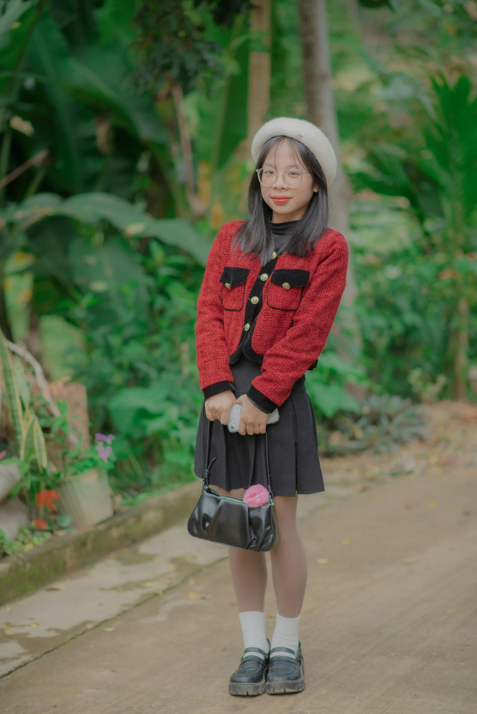 a woman wearing a red and black jacket and hat, and holding a purse