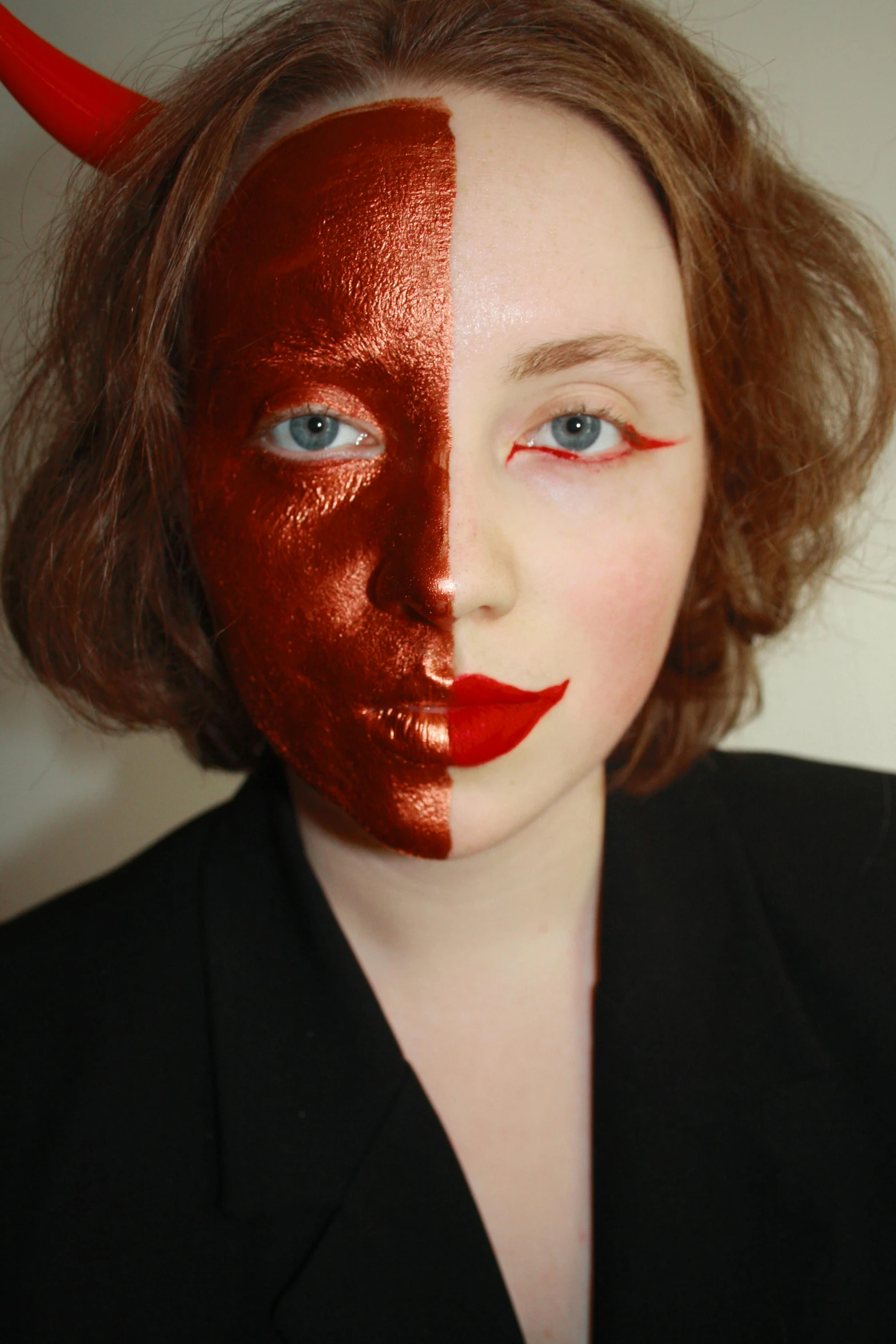 a woman in red lipstick is wearing a devil mask