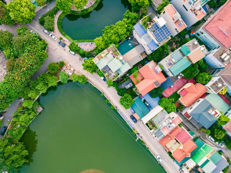 a small aerial view of an intersection with buildings, green pond, and winding street