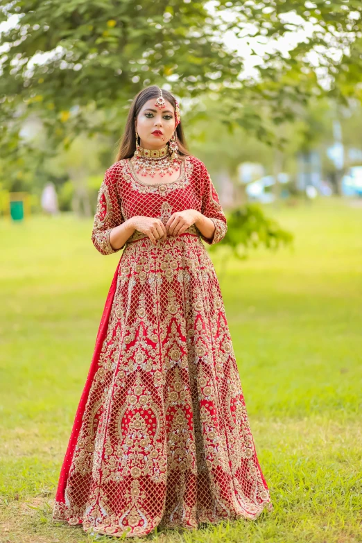 an indian woman poses on the grass near a tree