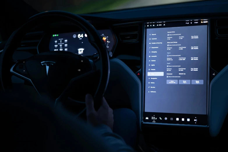 a person sitting in the driver's seat of a car at night using a touch screen