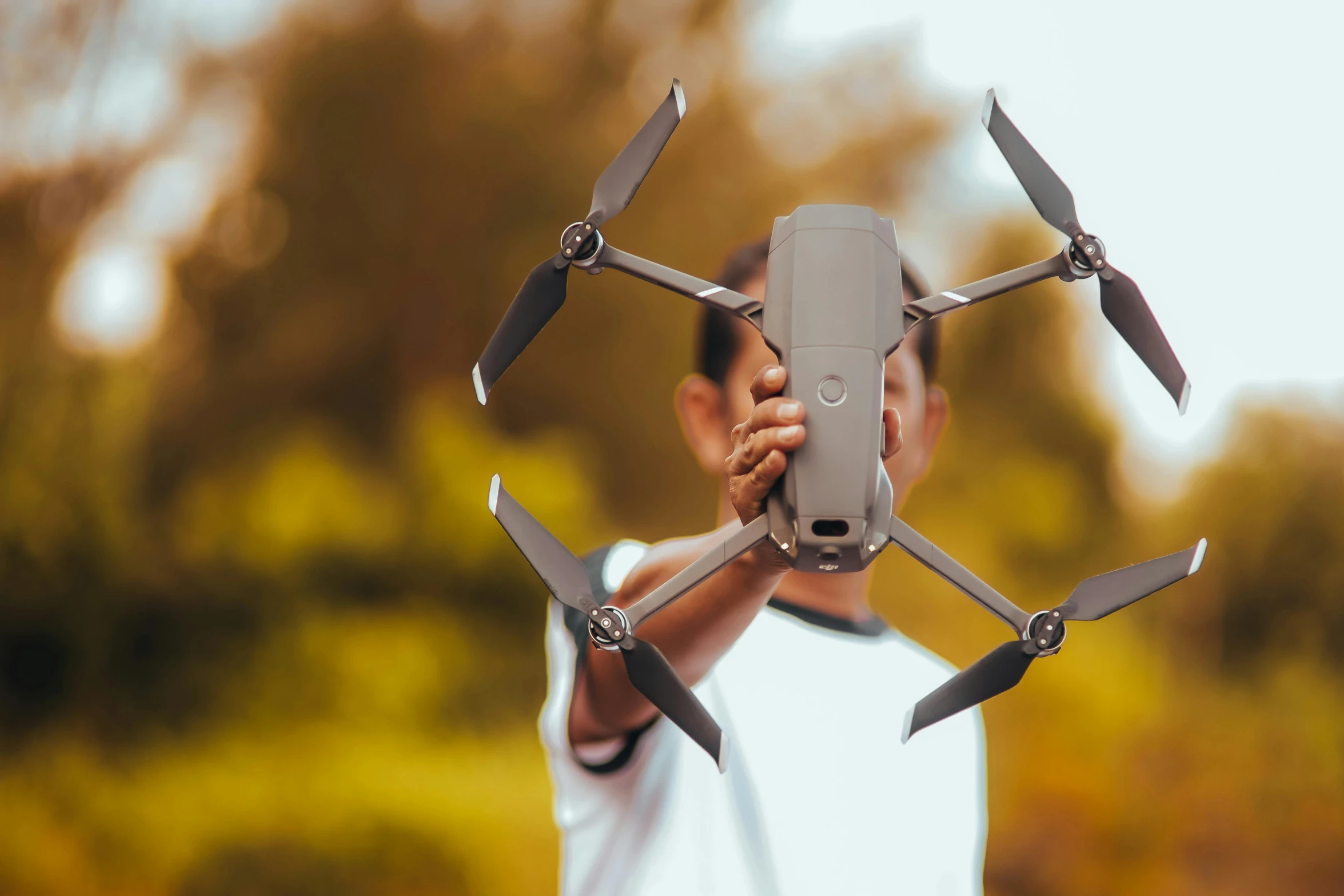 a man holding onto the blade of a tiny flying quadcopter