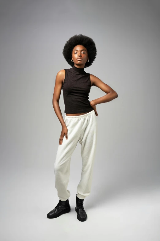 woman wearing a black top and white pants posing