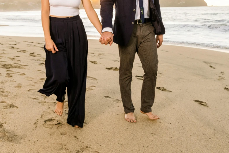 the man and woman are walking along the beach