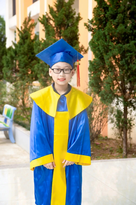 a child wearing a graduation gown and holding a big yellow book