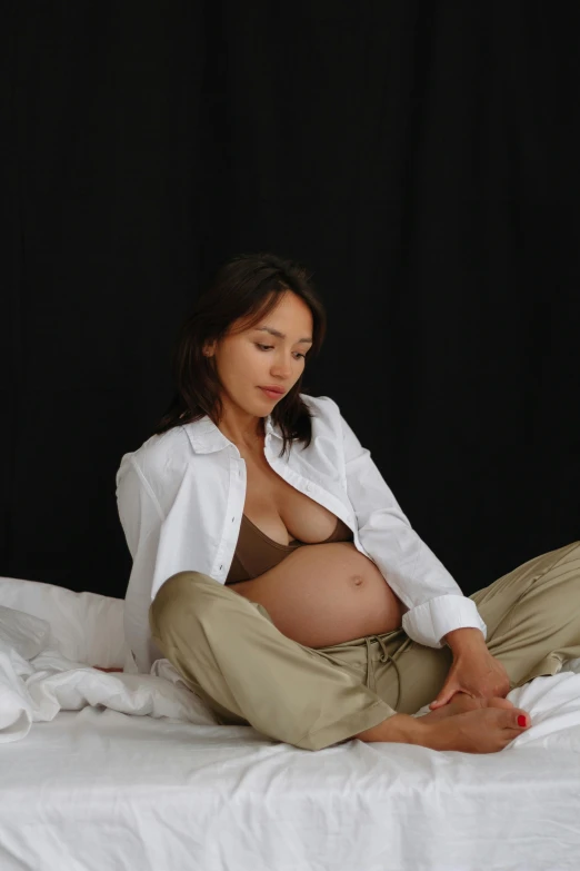 a pregnant woman sits on her stomach while posing for the camera