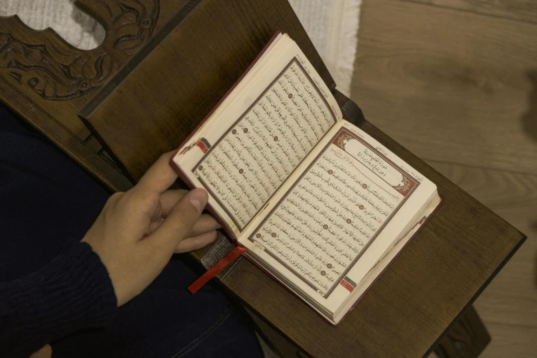 the person is reading the book on the wooden chair