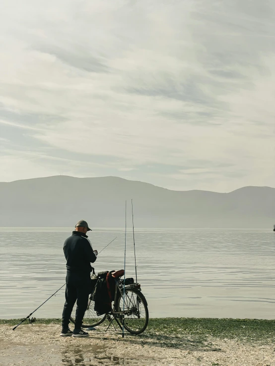 a man standing next to a bike on a beach