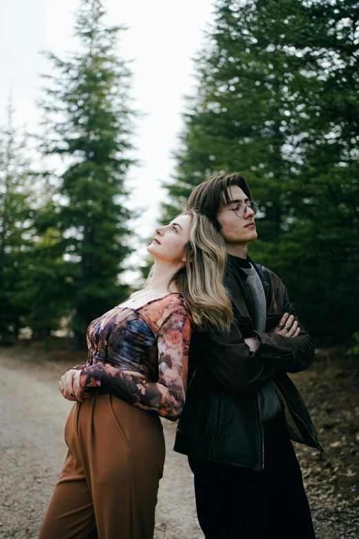 two people are standing close to each other in the middle of a dirt road