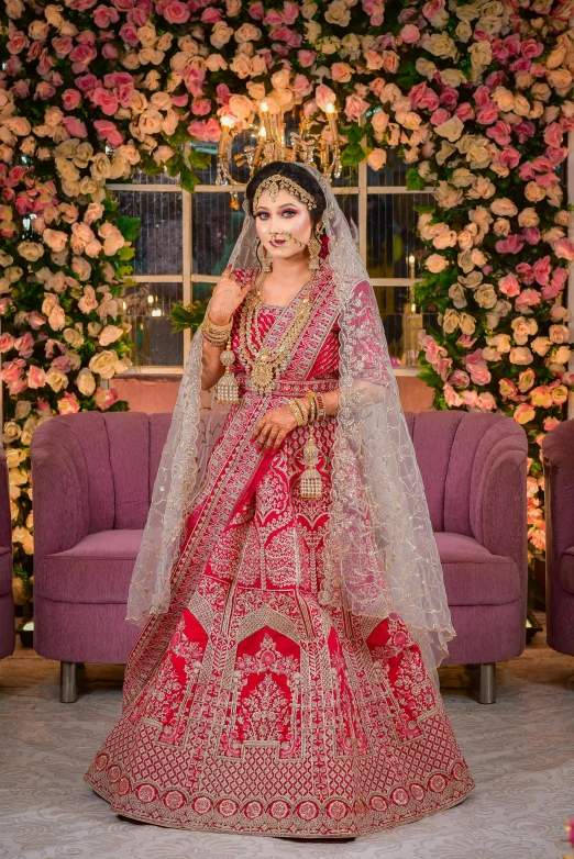 a beautiful bride poses with a veil in front of a flower wall