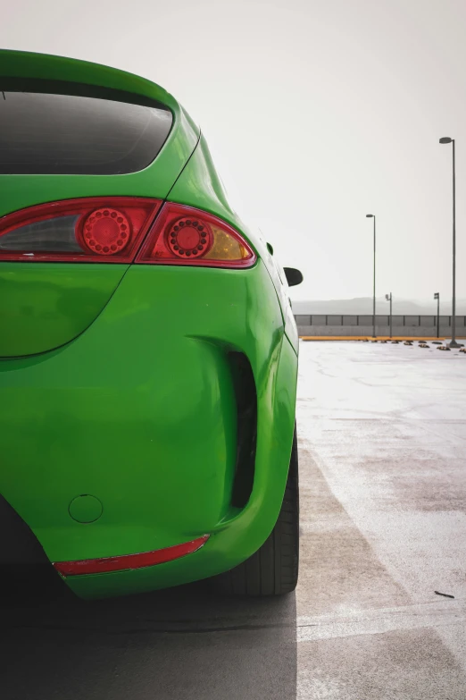 a green colored car is parked in the parking lot