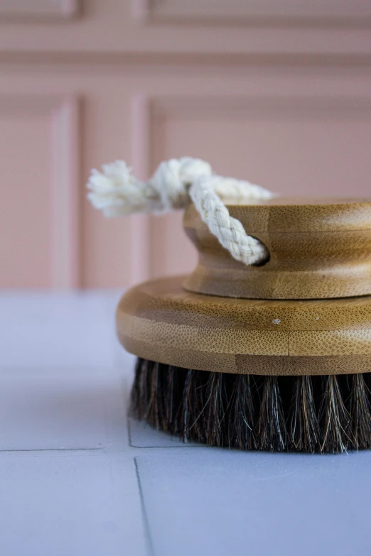 a shaving brush that is next to a pink wall