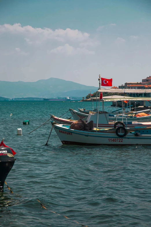 several boats tied up to the shore with a flag on it