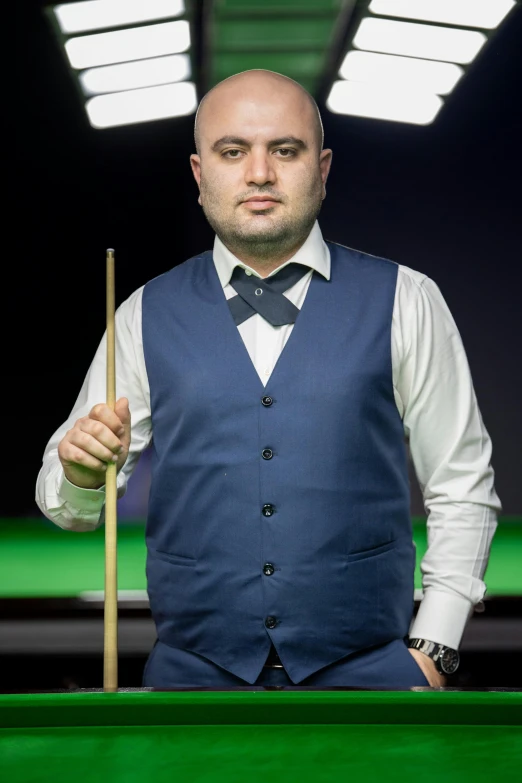 a man in a vest holding a cue in a pool