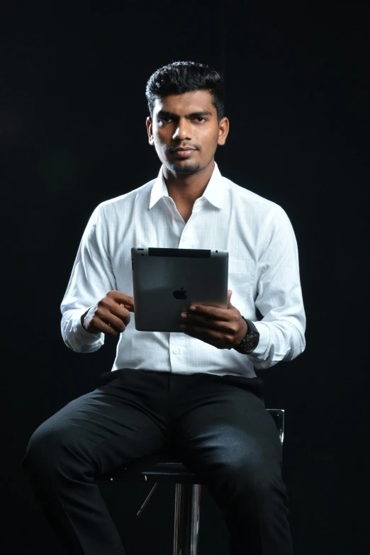 a man in a white shirt and black pants is using a tablet