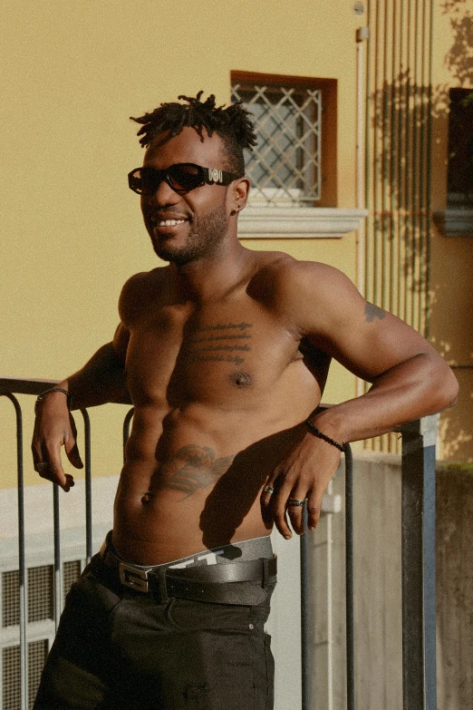 a man with shirt off stands next to a balcony