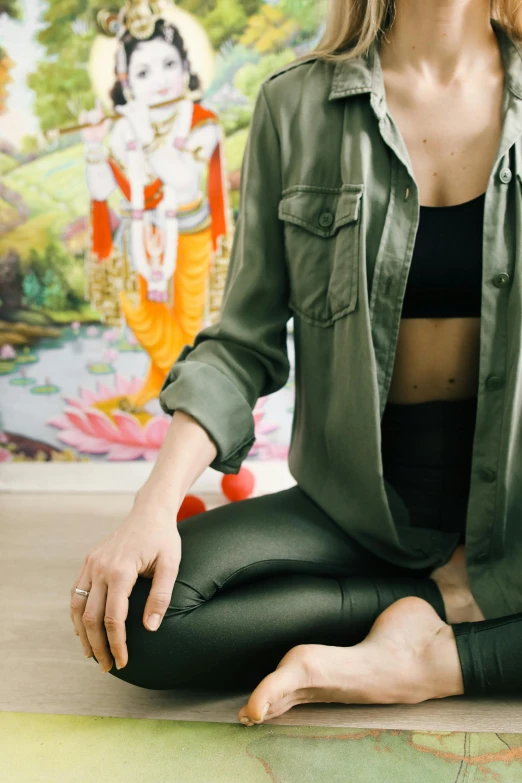 a woman in a green shirt is sitting on a yoga mat