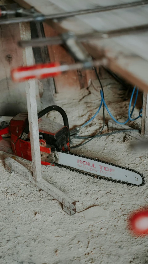 an old red chainsaw is sitting in the sand