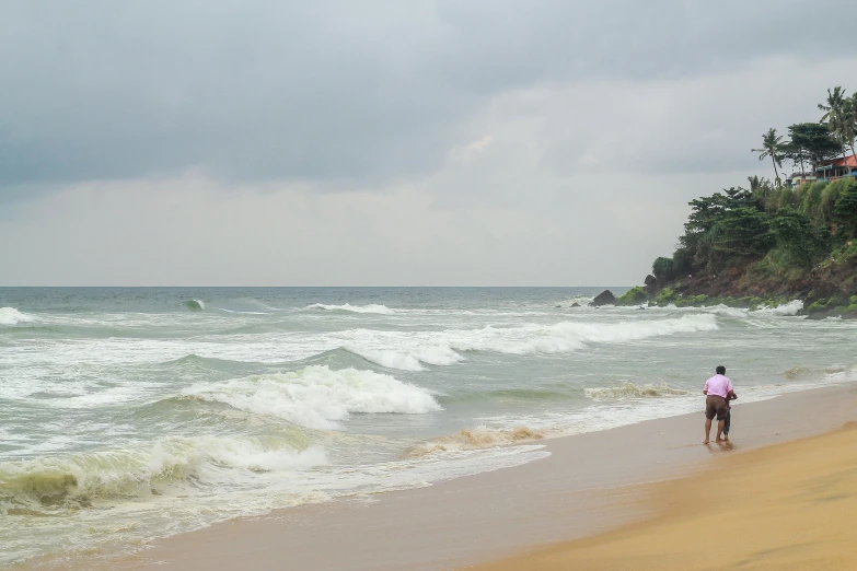 a lone man walking in the sand at the ocean