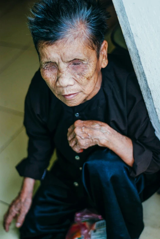 old woman in black sitting on floor holding soing