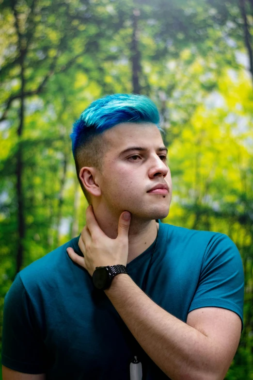 a young man with blue hair is leaning against a wall