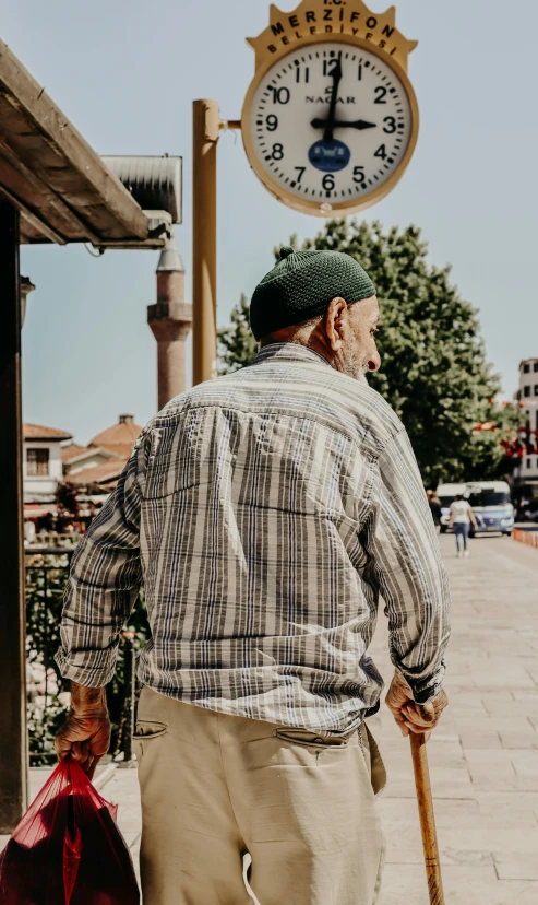 the man is holding a cane standing next to a clock