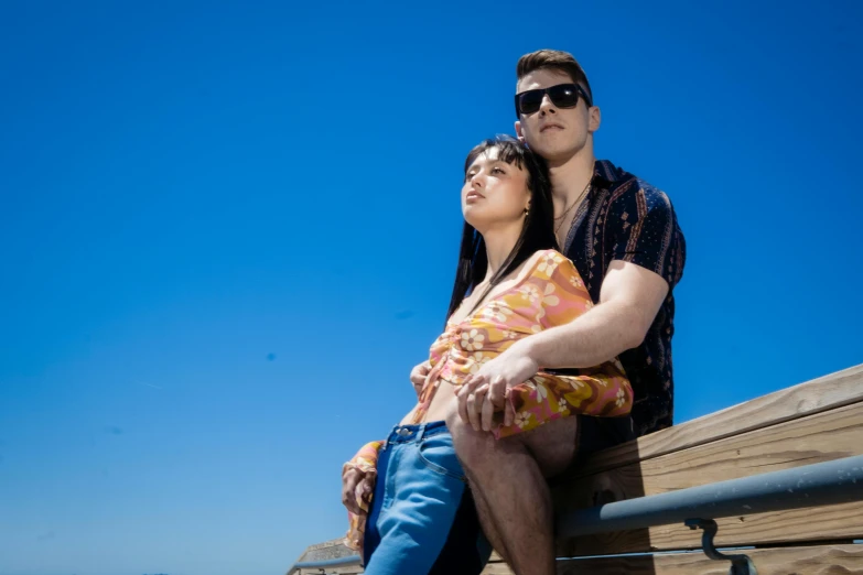 a couple sitting together while they look at the blue sky