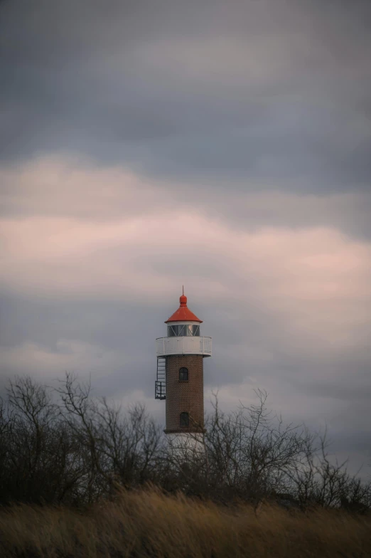 a red top light house standing among some dark clouds