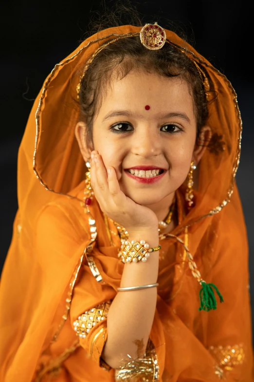 a  in a yellow sari and jewelry is smiling